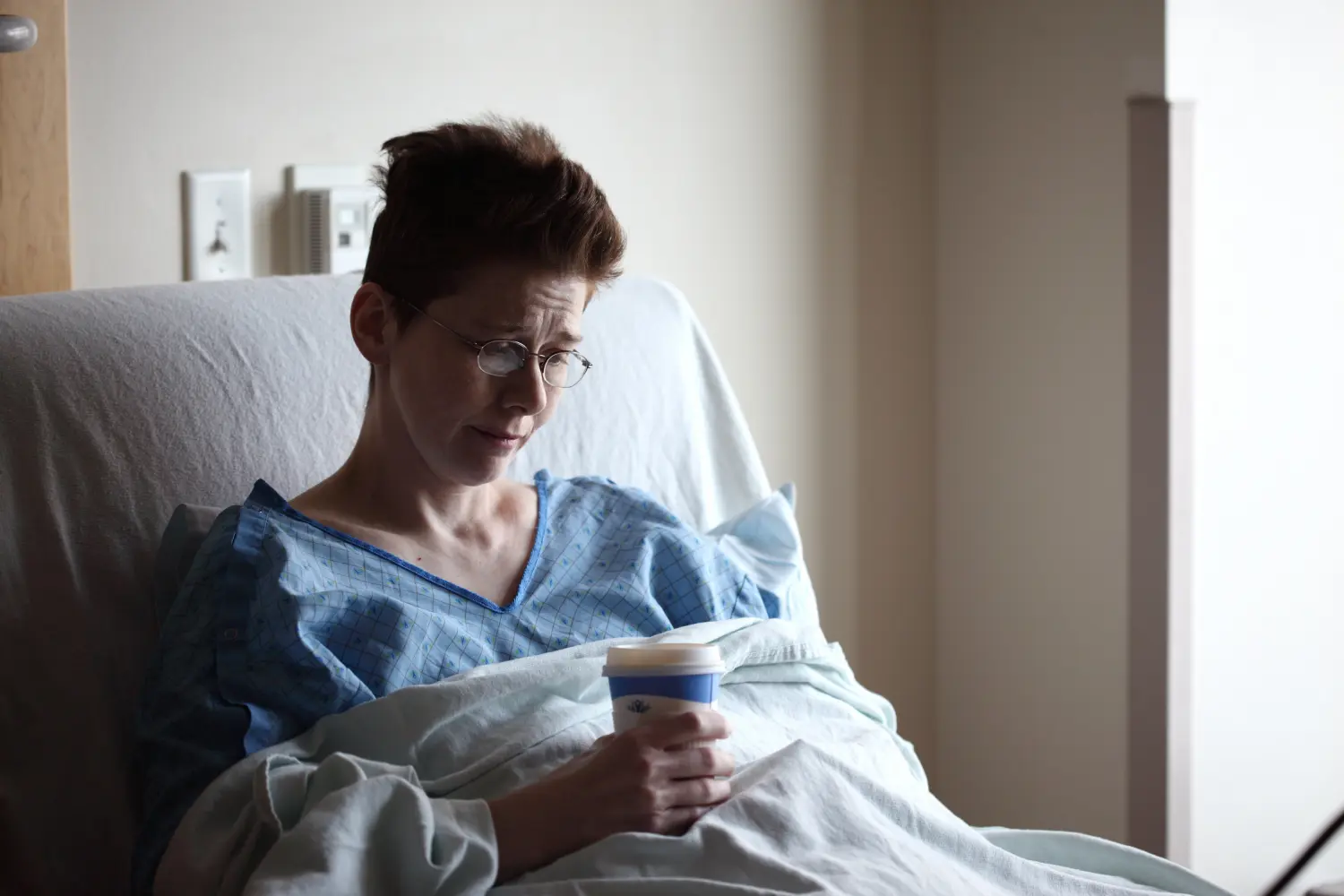 Ein psychotischer Patient hält eine Tasse Kaffee in der Hand, während er auf dem Krankenhausbett ruht